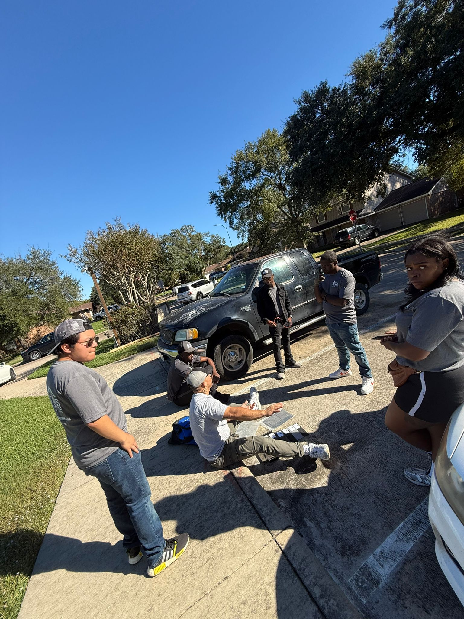 DC Pines Roofing crew reviewing project materials in a Houston driveway during a bilingual briefing