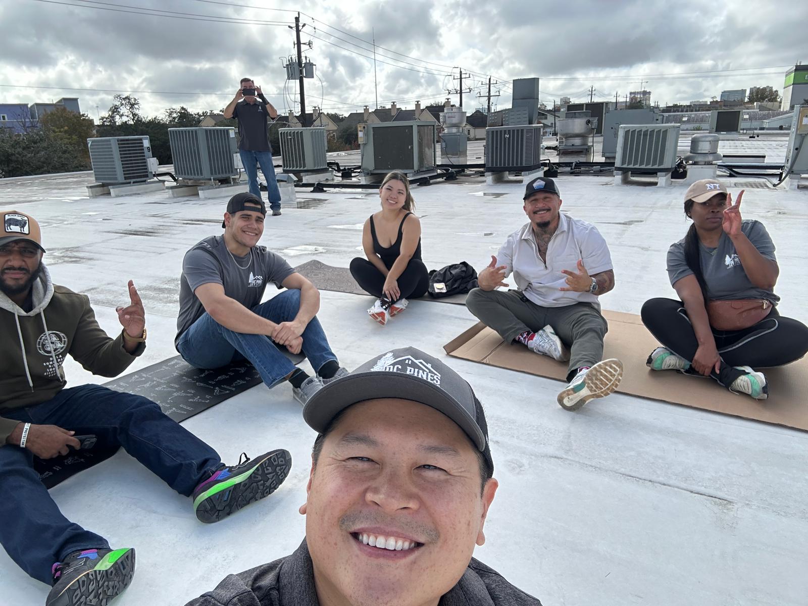 DC Pines Roofing team members taking part in a team wellness session on a Houston rooftop