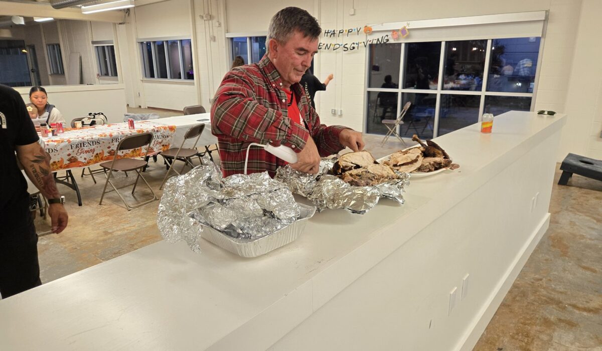 DC Pines Roofing owner carving turkey at the company Friendsgiving celebration in Houston