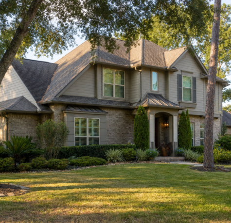 Houston suburban home in late summer with mature live oak and pine trees surrounding the exterior