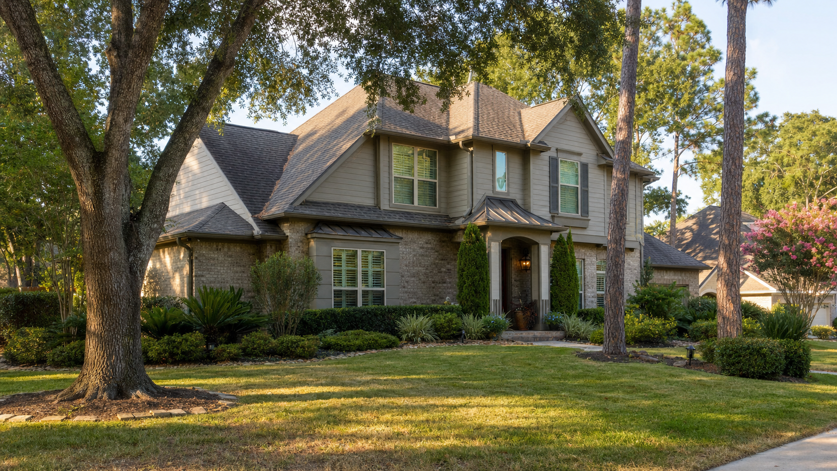 Houston suburban home in late summer with mature live oak and pine trees surrounding the exterior