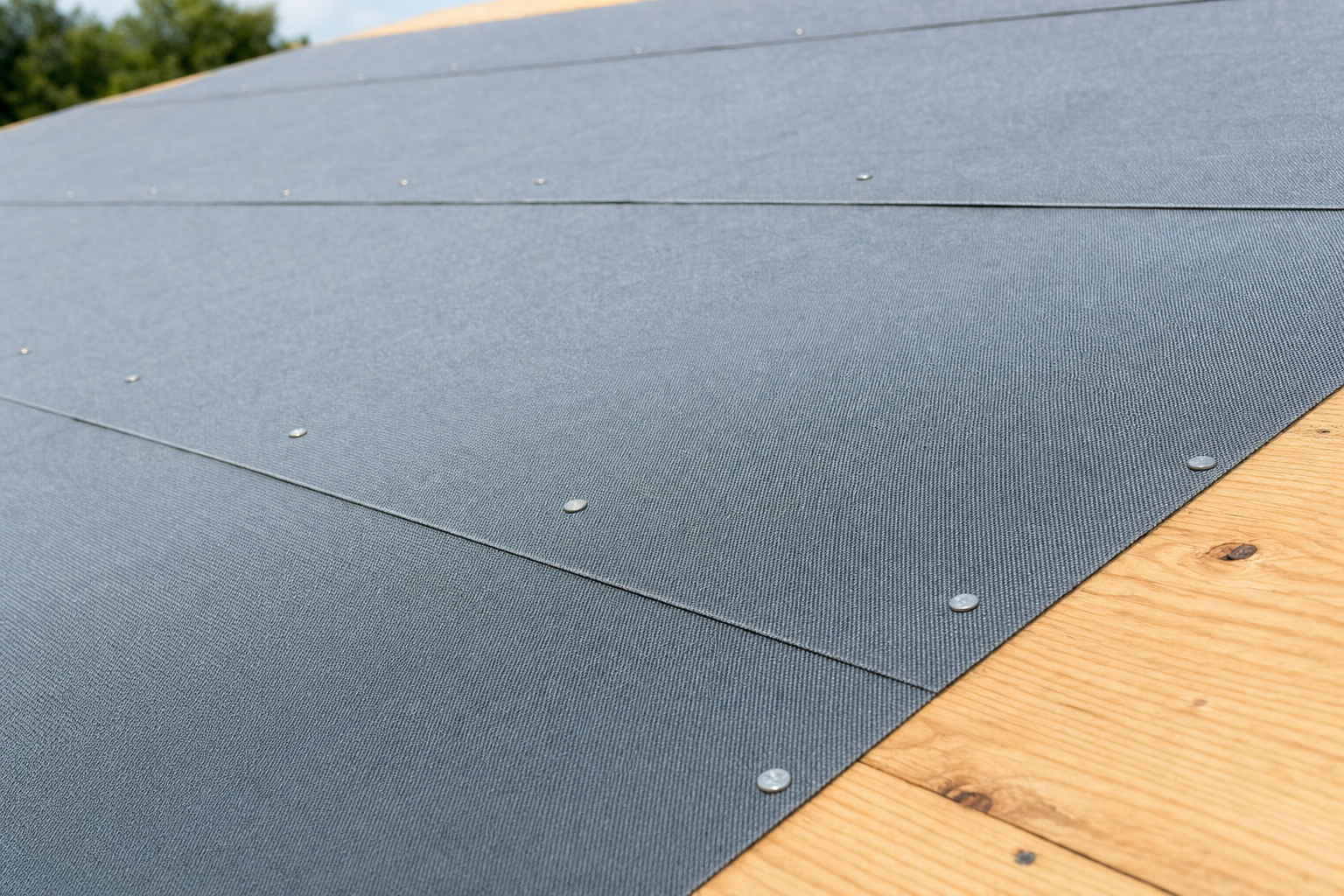 Synthetic roof underlayment installed with proper cap nails and overlapping seams on plywood decking, a critical layer beneath Houston roofing