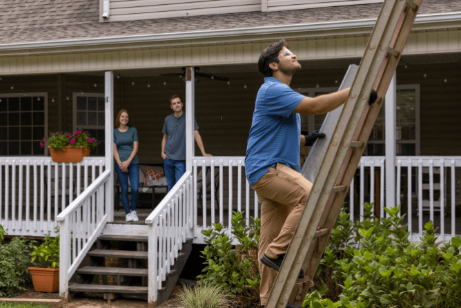 Roofing installer on ladder installing LeafBlaster Pro gutter guards
