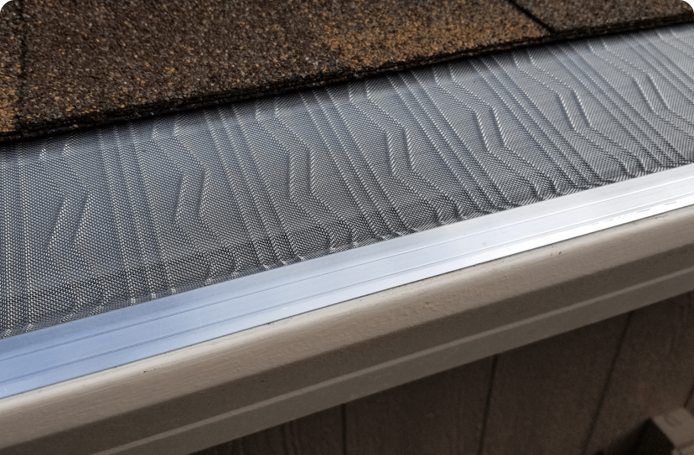 LeafBlaster Pro Z-Bend stainless steel micro-mesh installed along a gutter edge on a brown shingle roof