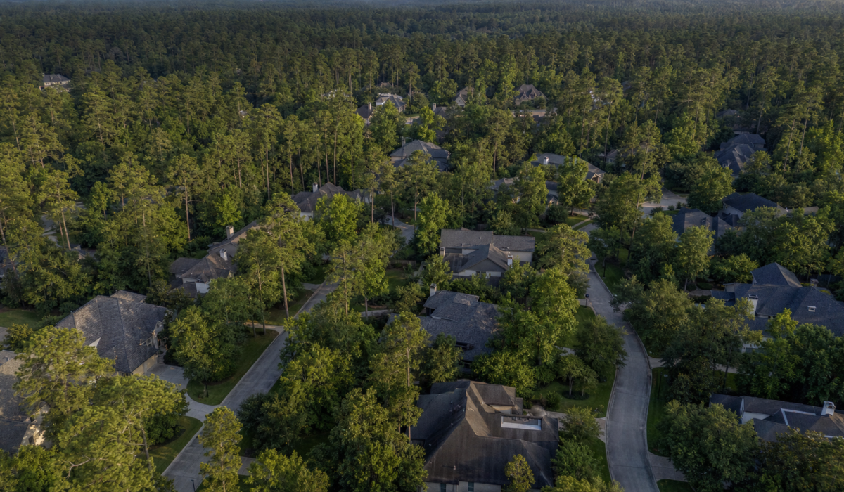 Aerial view of a Woodlands Texas neighborhood surrounded by dense pine and oak canopy