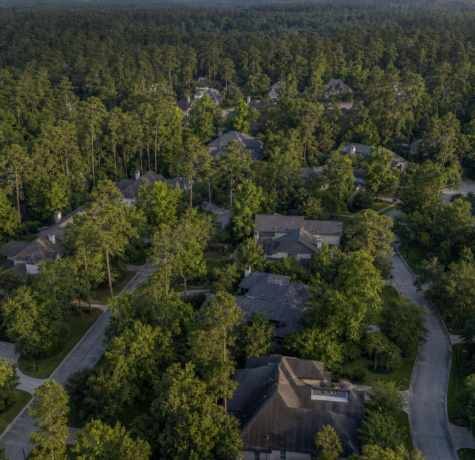 Aerial view of a Woodlands Texas neighborhood surrounded by dense pine and oak canopy