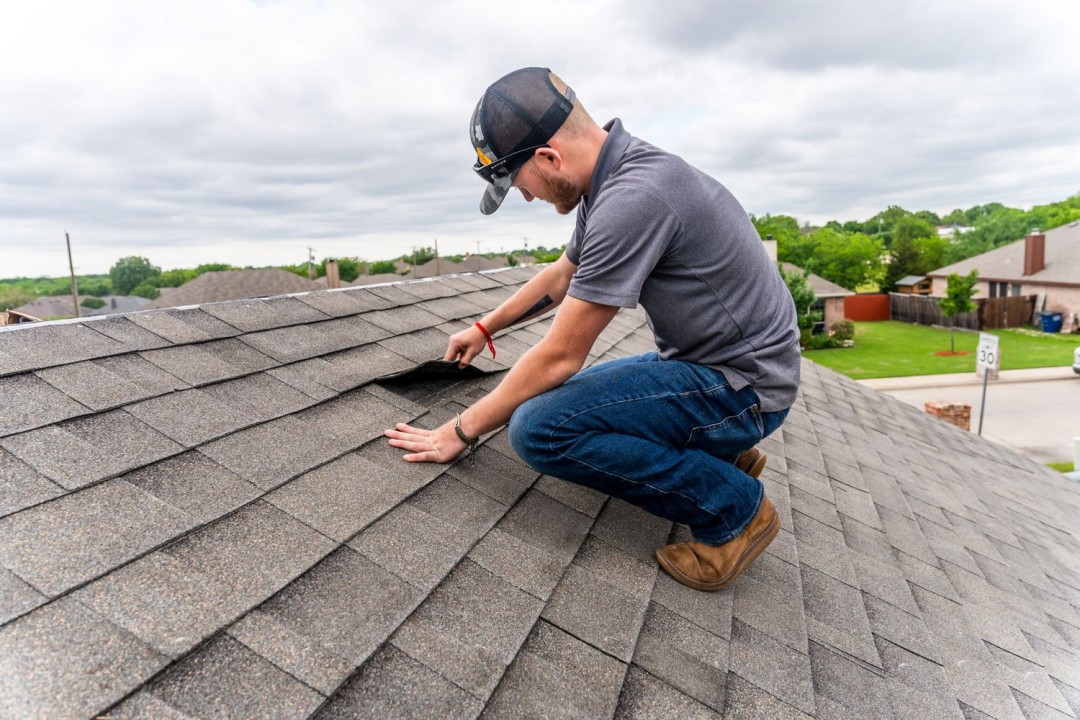 DC Pines Roofing technician on a Houston-area roof inspecting shingles during a routine service visit