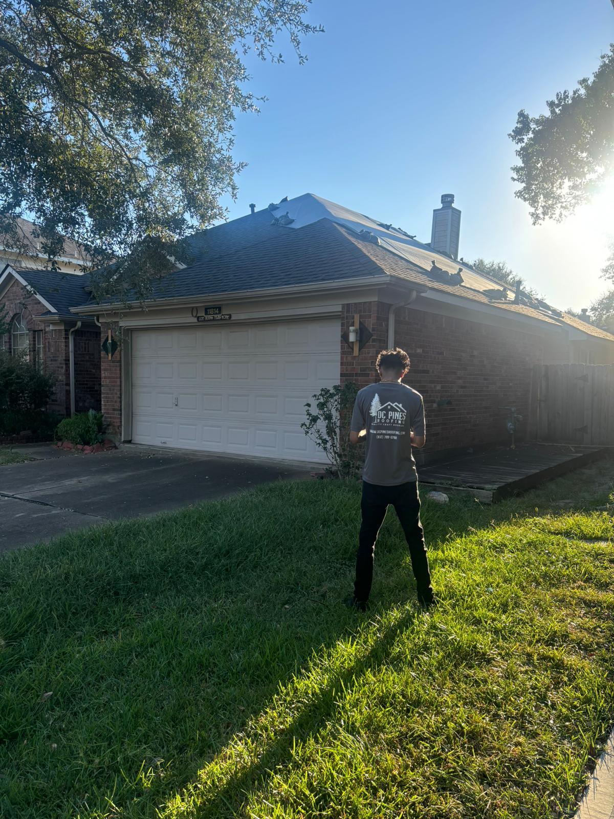 DC Pines Roofing crew member reviewing a completed shingle install from the front yard of a Houston home