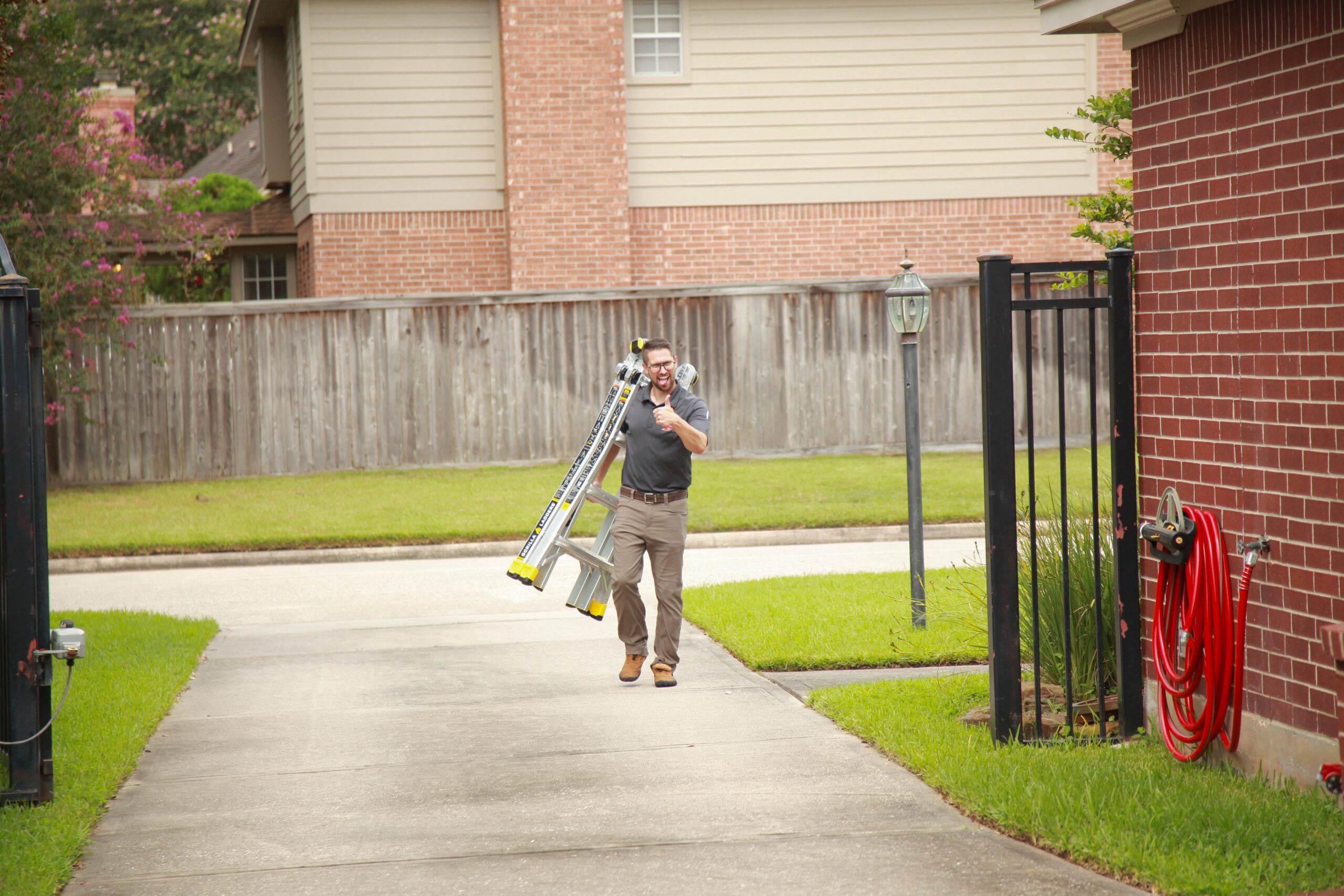 DC Pines Roofing crew member carrying ladder to a Houston jobsite