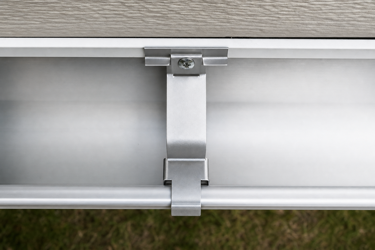 Hidden gutter hanger bracket clipped inside a K-style gutter with a stainless hex-head screw