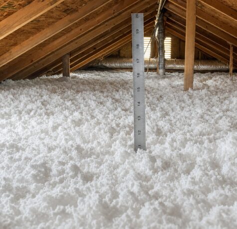 Deep blown-in fiberglass attic insulation with ruler showing depth for Houston R-49 target