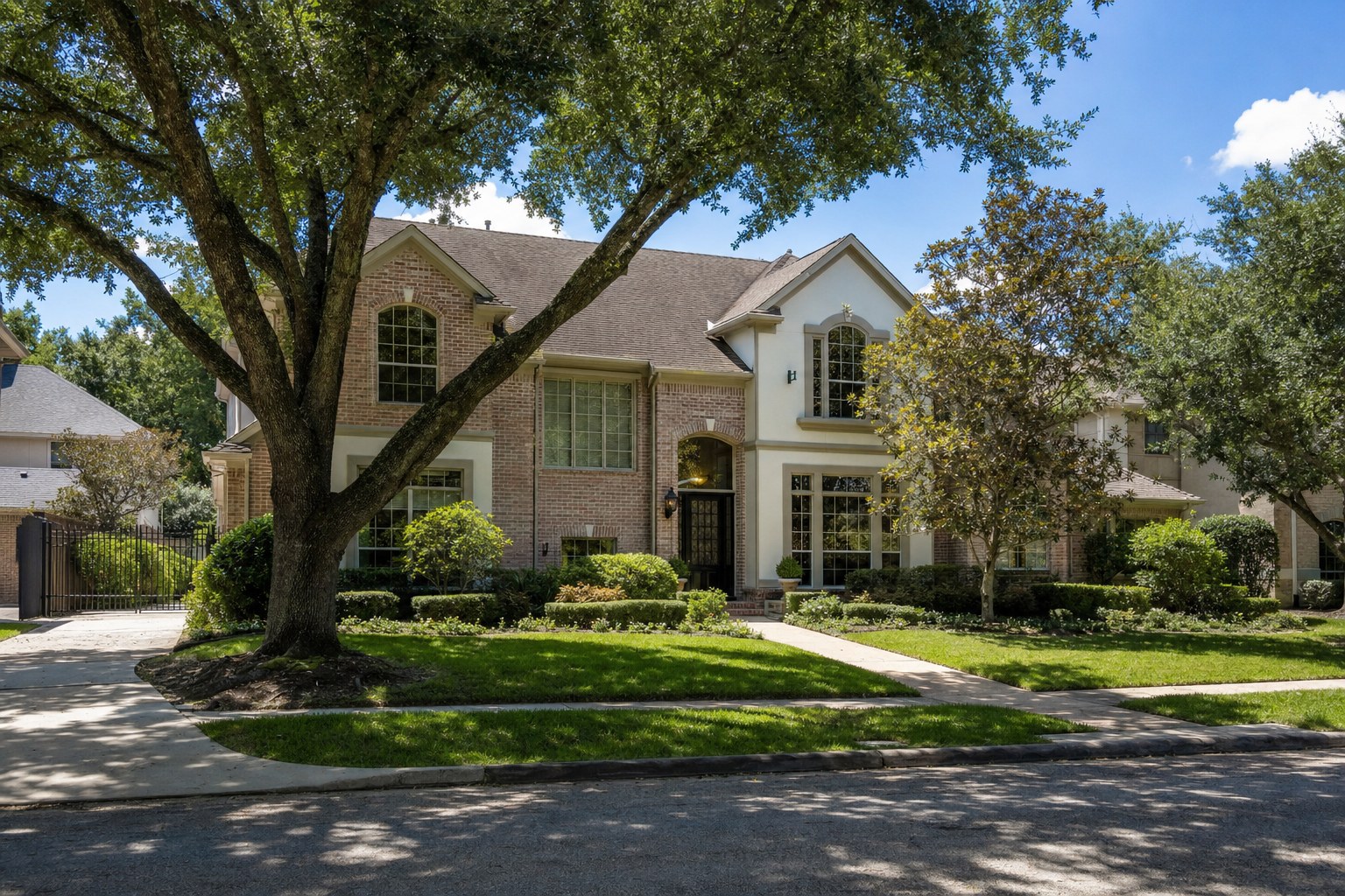 Two-story Houston brick and stucco home under live oaks
