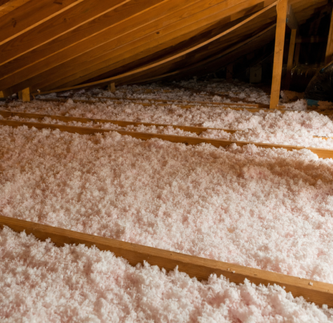 Houston attic with thick blown-in fiberglass insulation covering attic floor between wood ceiling joists showing depth for R-38 to R-60 target