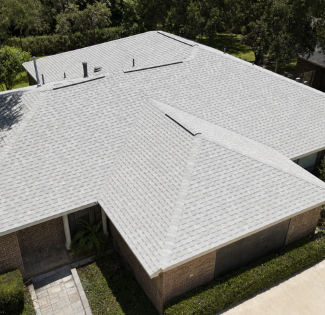 Aerial view of a Houston hip roof covered in light-colored cool-roof asphalt shingles designed for high solar reflectance