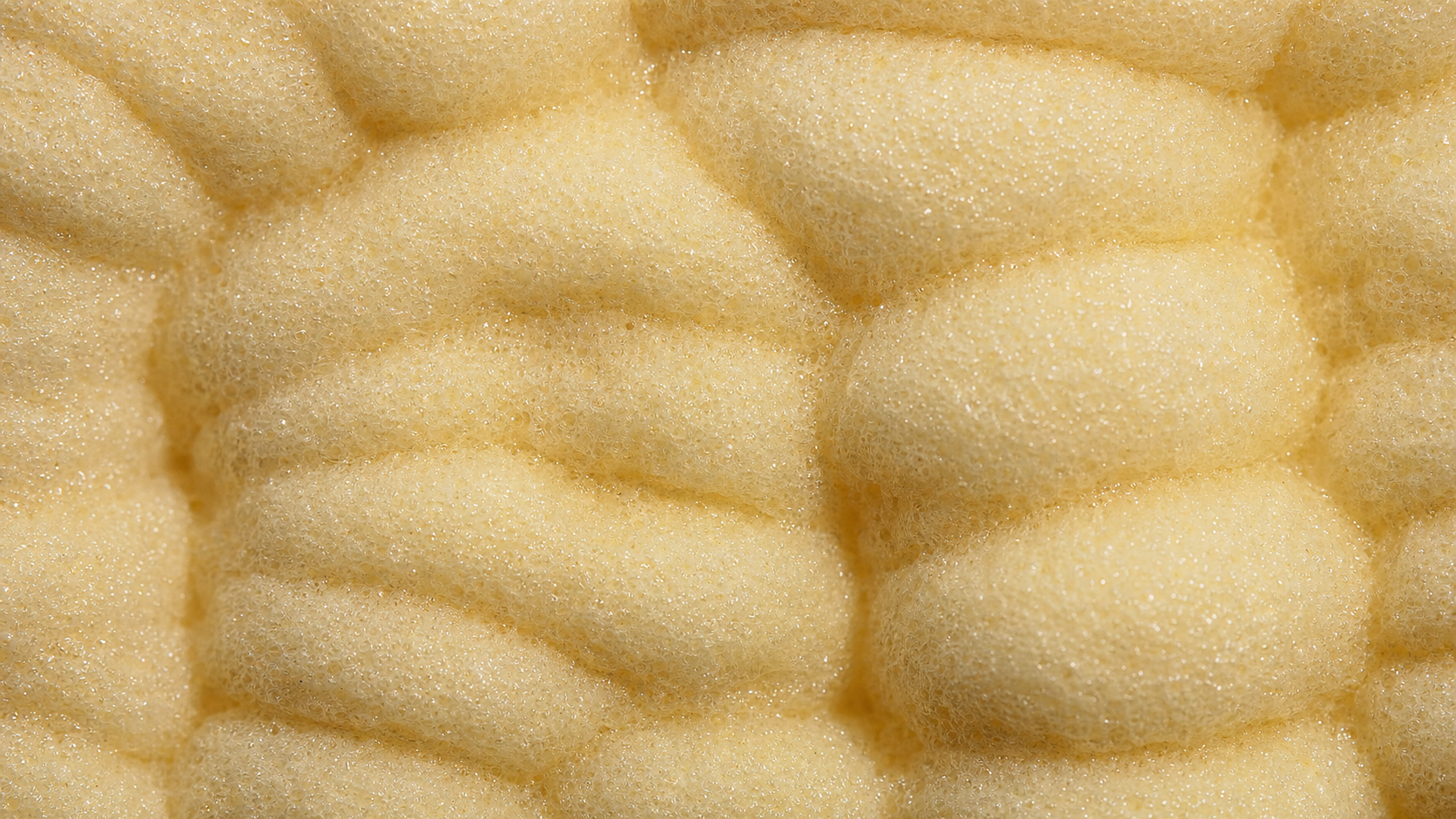 Extreme macro of dense closed-cell polyurethane spray foam showing tight closed-bubble surface texture