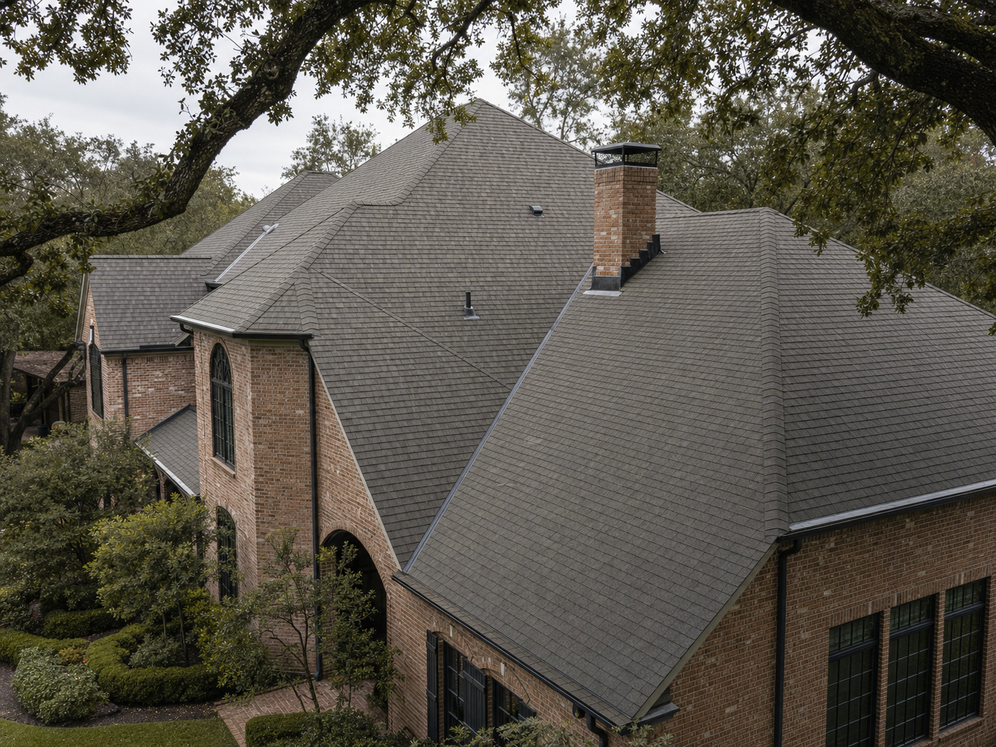 Complex hip-and-valley Houston Memorial estate roof with multiple planes intersecting near a chimney flashing
