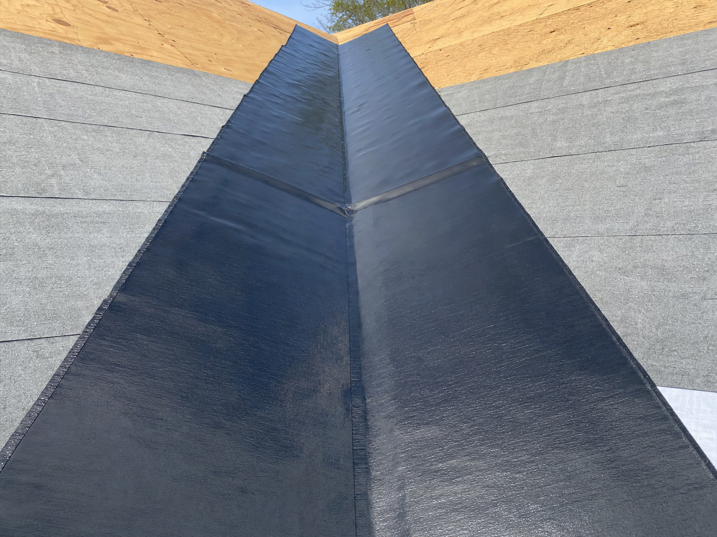 Rubberized peel-and-stick self-adhered ice and water shield membrane applied at eaves and valleys of a Houston roof deck