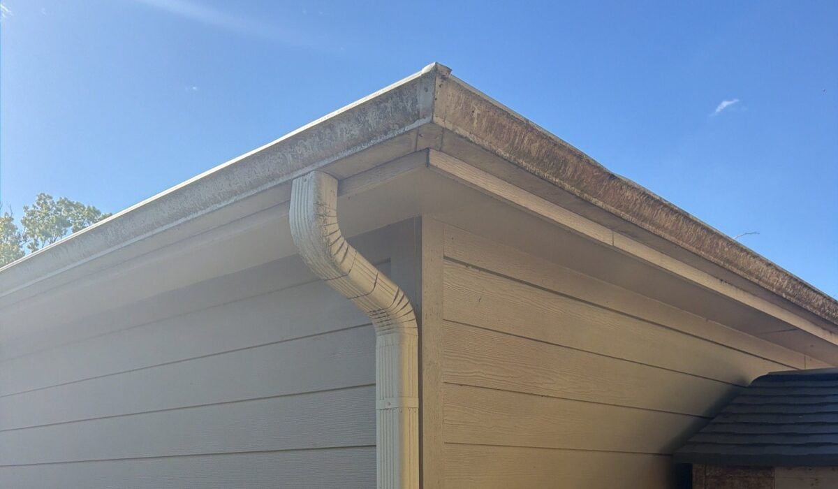 Aluminum gutter corner and downspout on a Houston home with streaking along the gutter edge