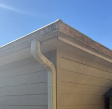 Aluminum gutter corner and downspout on a Houston home with streaking along the gutter edge