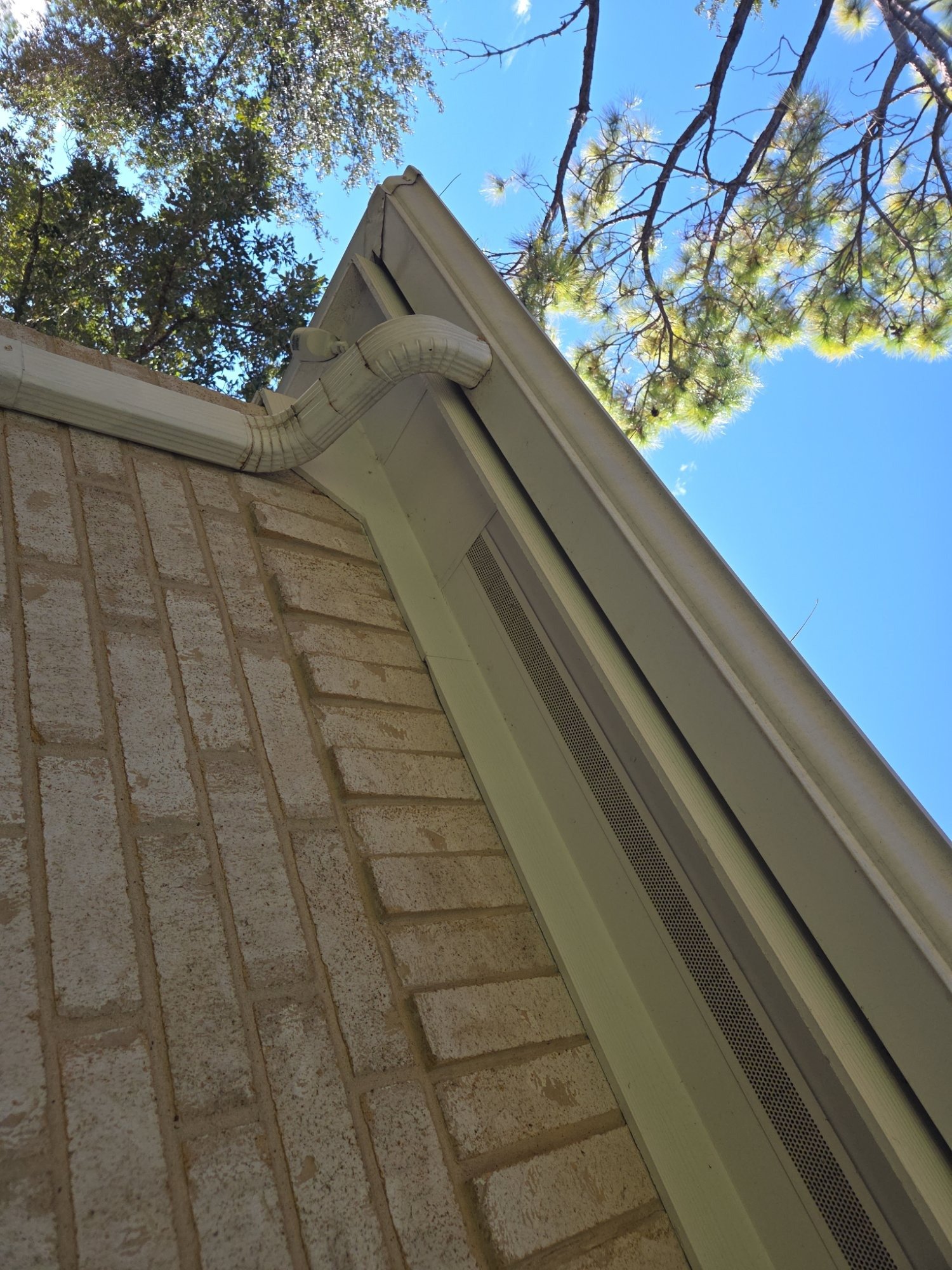 Eave, soffit vent, and gutter line on a brick Houston home documented during a roof inspection