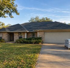 New charcoal shingle roof on a brick Houston home on a clear fall afternoon